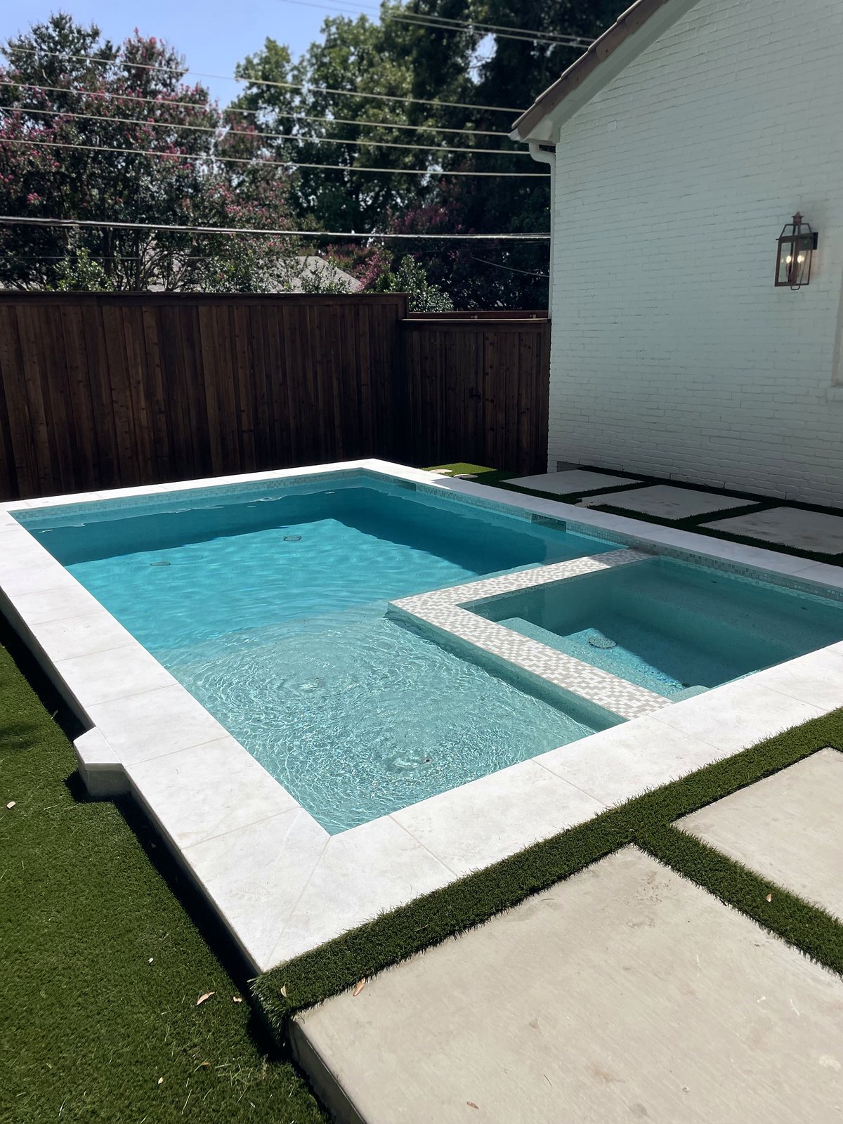 Close-up of the spa with mosaic tile edge, clear blue water and bright white stone coping — completed by Infinity Group DFW in Dallas, Texas